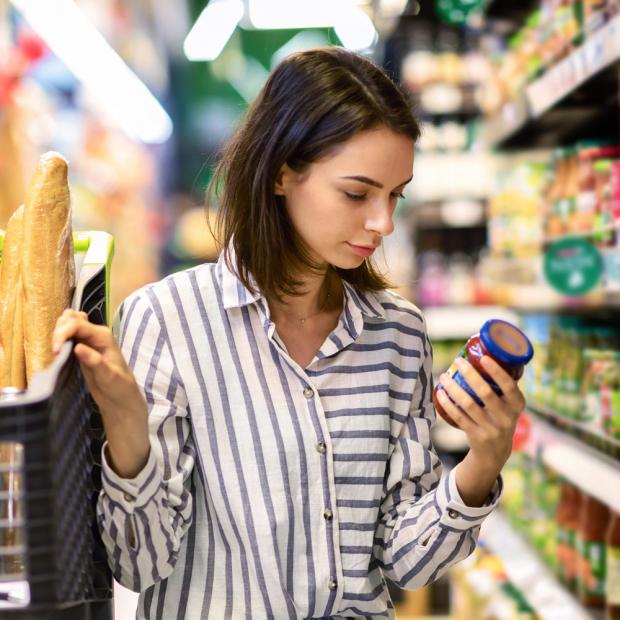 Frau sieht sich ein Produkt im Supermarkt genauer an.
