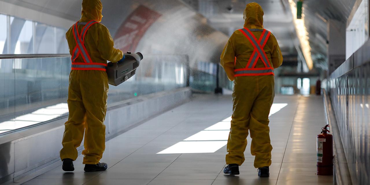 Flughafen wird durch Arbeiter in Schutzanzügen desinfiziert