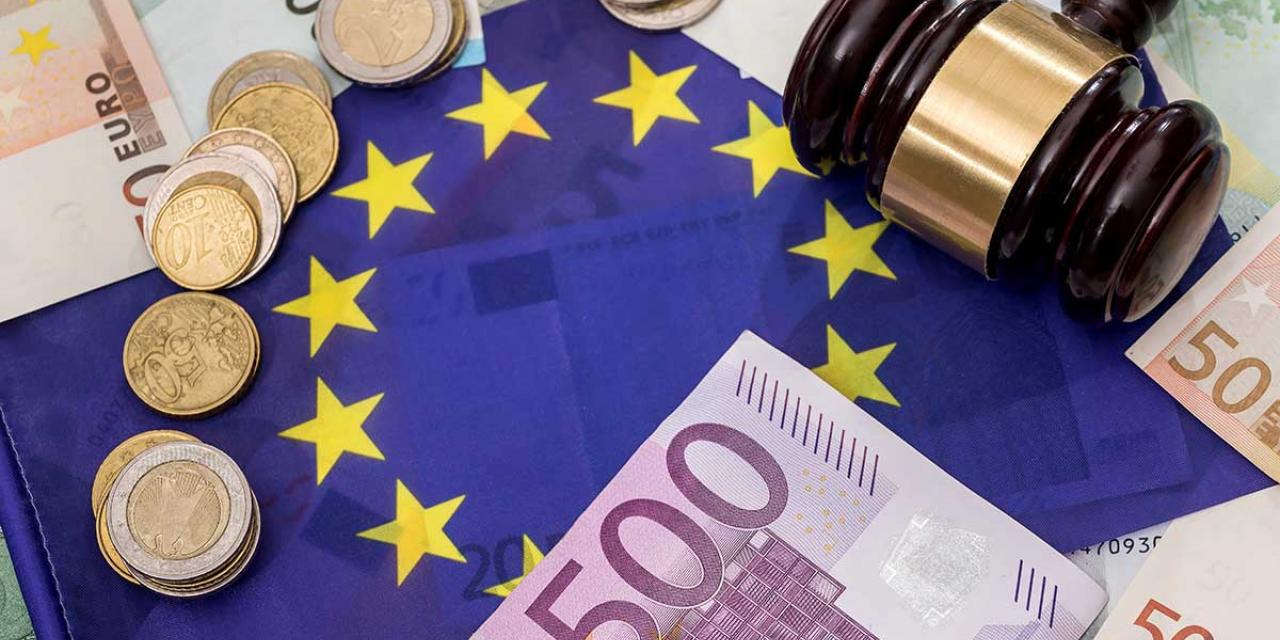 Euro notes and coins and a court hammer lie on European flag