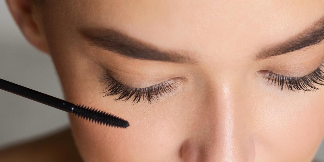 Dame mit geschlossenen Augen hält Mascara vor ihren WImpern