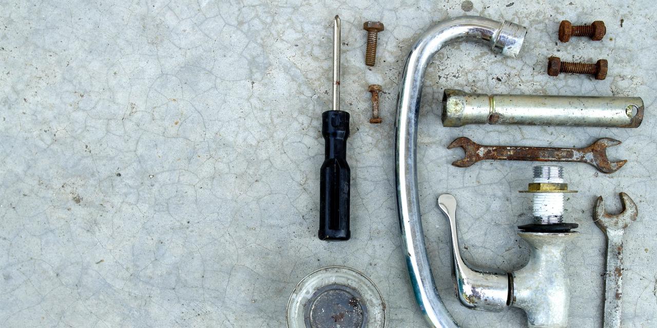 zerlegter Wasserhahn und rostige Schraubenschlüssel