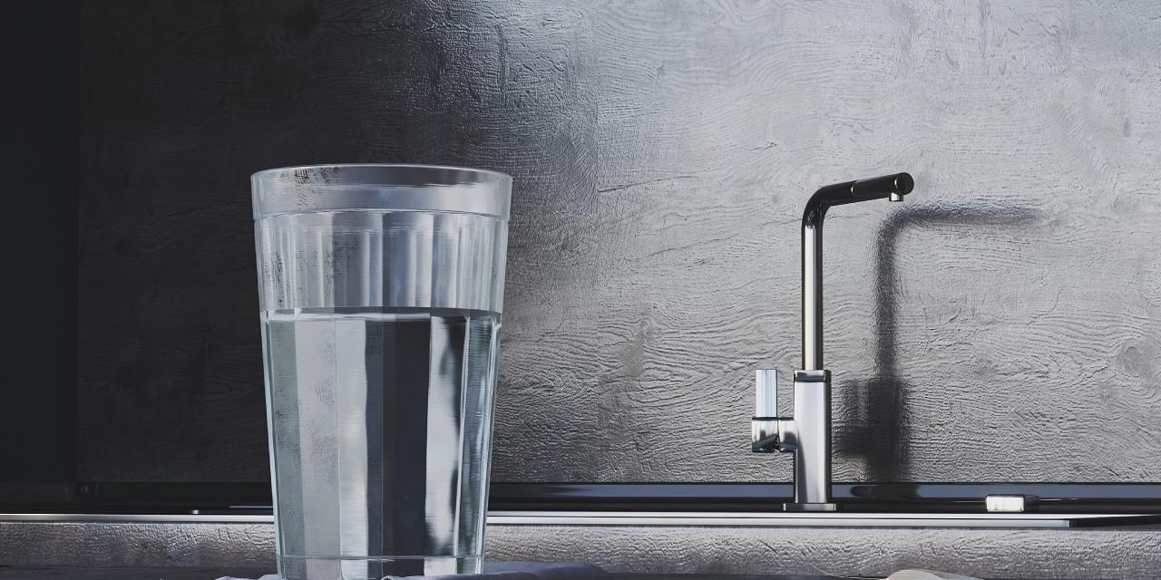 Wasserglas mit Trinkwasser steht auf Anrichte vor Spüle