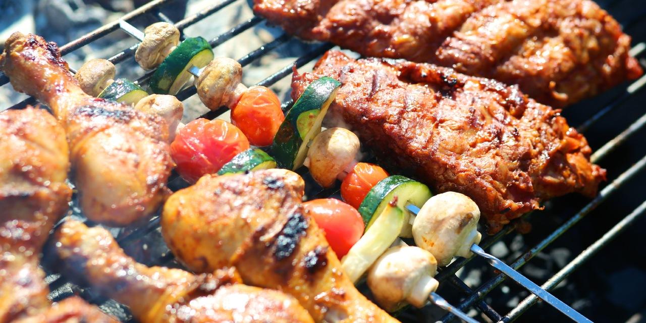 Fleisch und Gemüsespieße liegen auf einem Grillrost