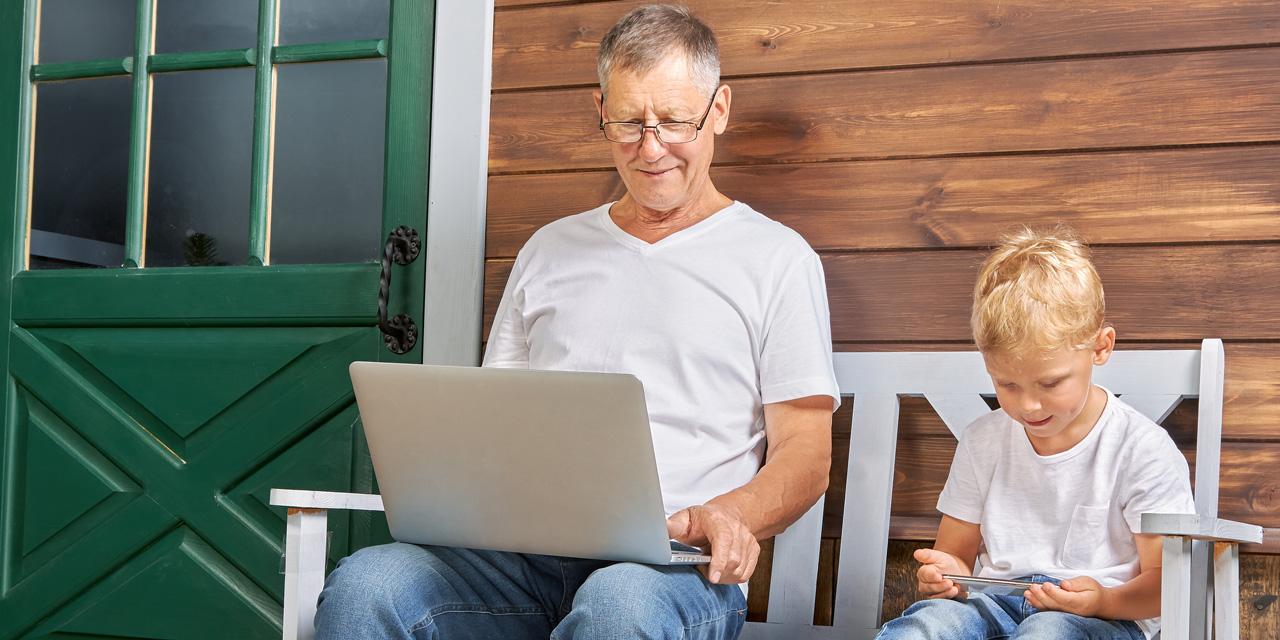 Großvater Enkel sitzen auf einer Bank Laptop Smartphone 