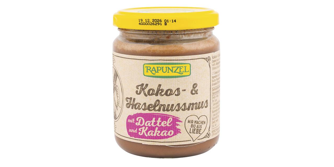 Ein Glas Kokos- & Haselnussmus vor weißem Hintergrund