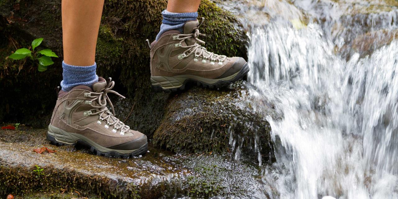 Wanderer mit Wanderschuhen neben einem Wasserfall