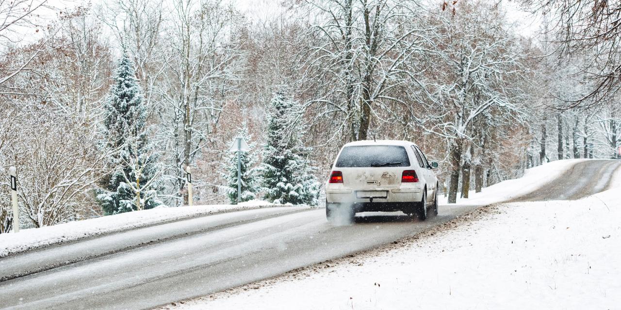 Weißes Auto auf winterlicher Fahrbahn
