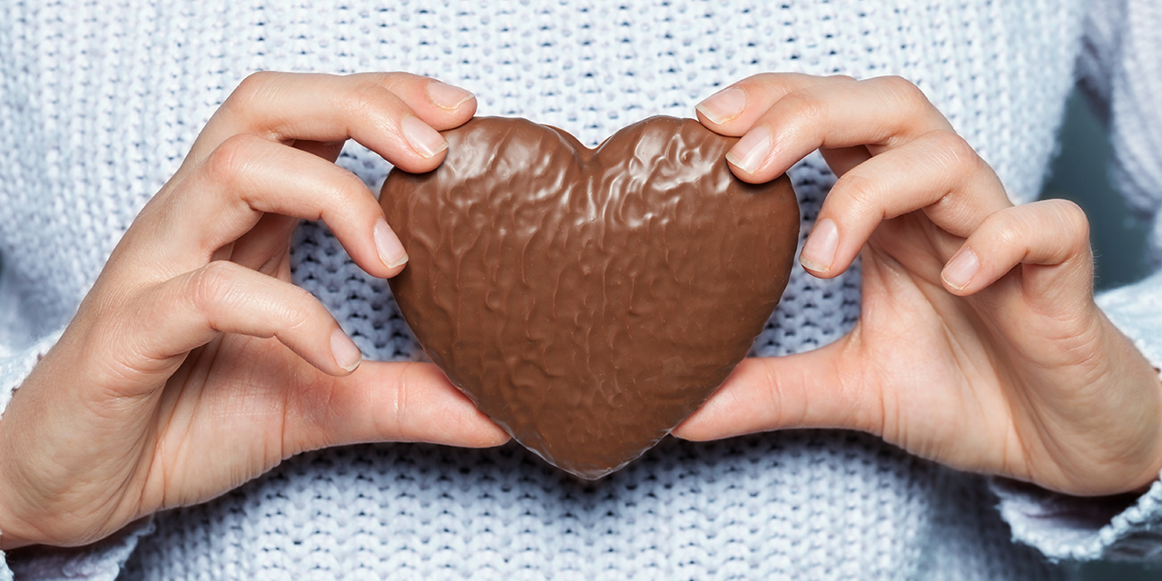 Eine Person hält einen mit Schokolade überzogenen Lebkuchen in den Händen.