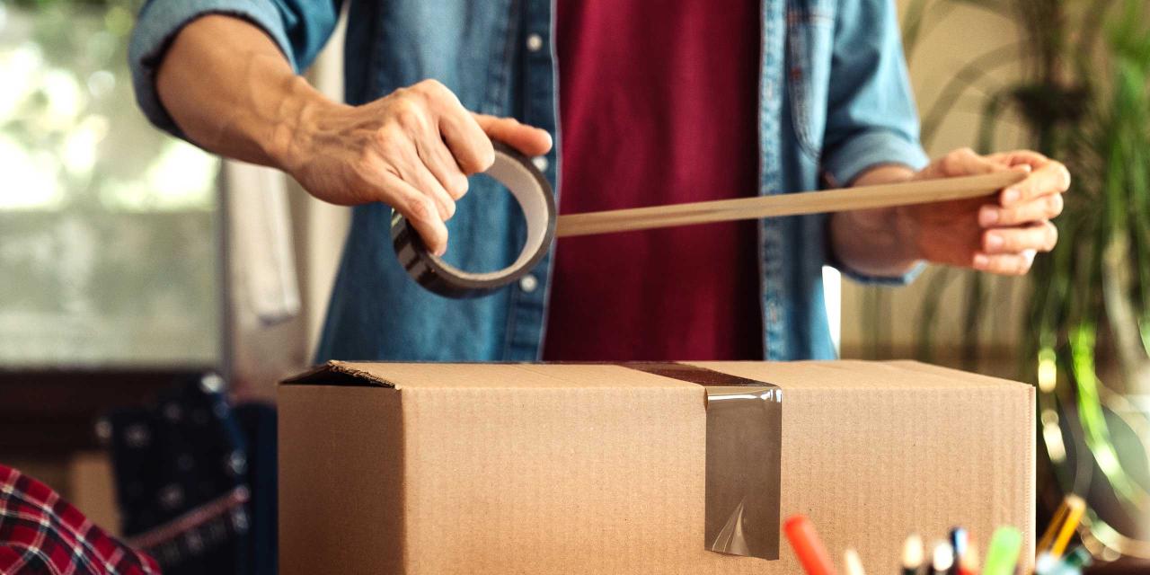 Mann hält Klebeband in Händen, um ein Paket zuzukleben und dann zurückzuschicken