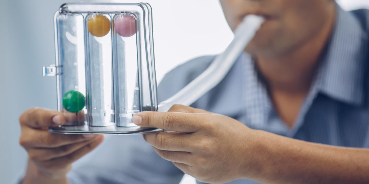 Ein Mann trainiert mit einem Atemtrainingsgerät, in dem drei Kugeln nebeneinander liegen. 