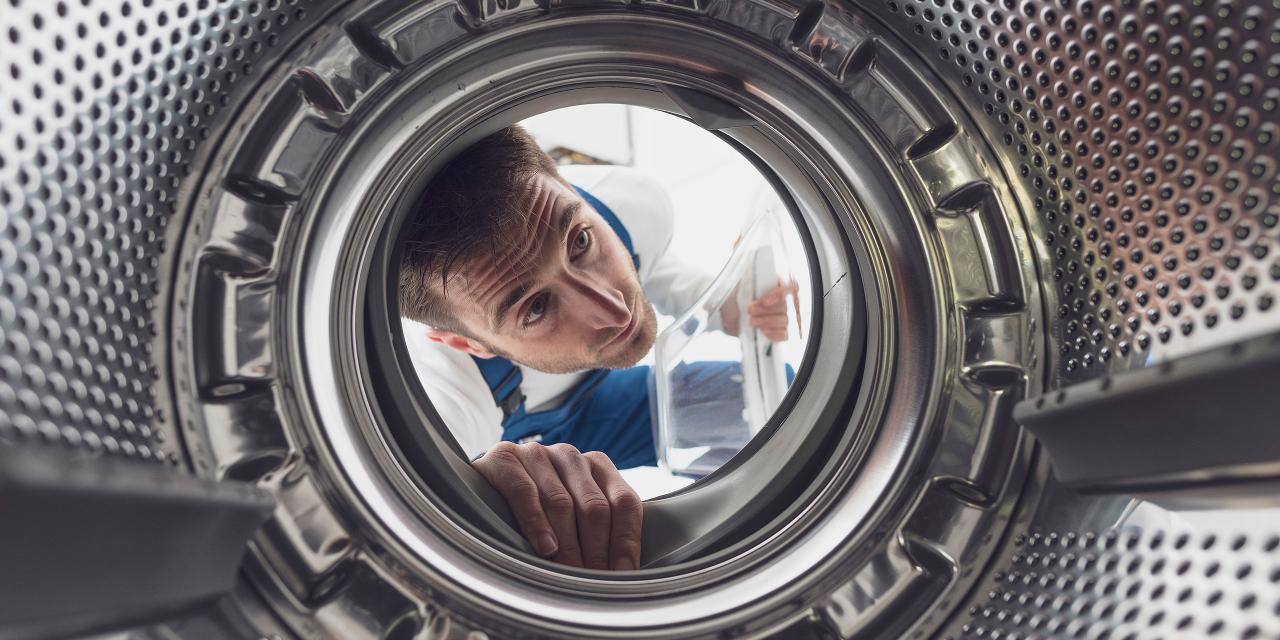 Installateur schaut in Waschmaschinentrommel