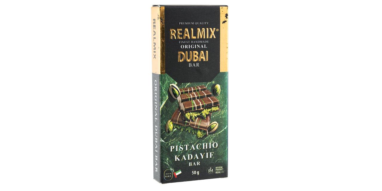 Die Verpackung der Realmix Dubai Bar mit goldener Beschriftung und abgebildeter Schokoladentafel vor weißem Hintergrund. 