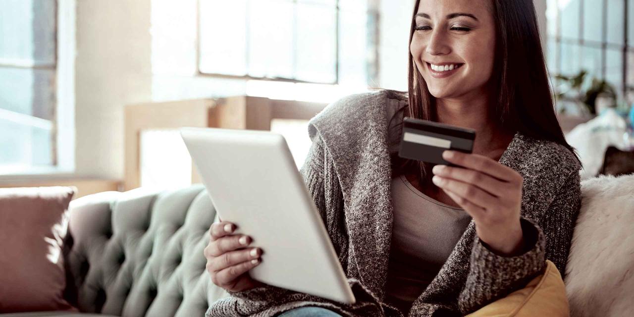 Frau hält die Kreditkarte in der einen und ein Tablet in der anderen Hand