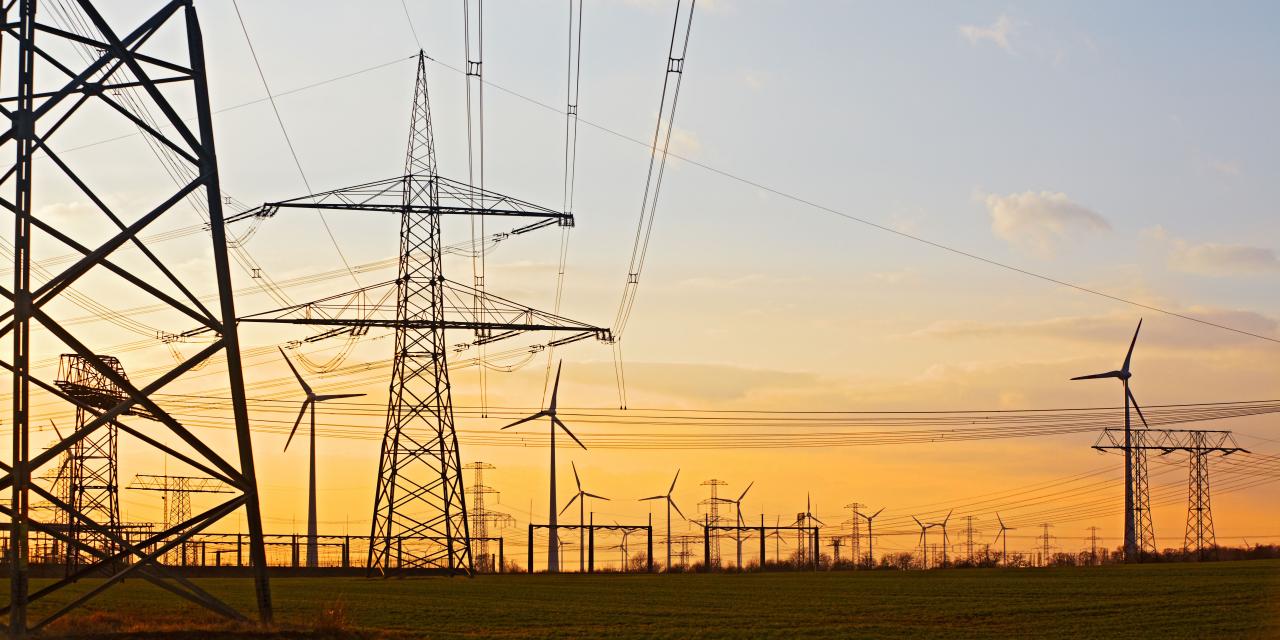 Strommasten und Windräder in Abenddämmerung