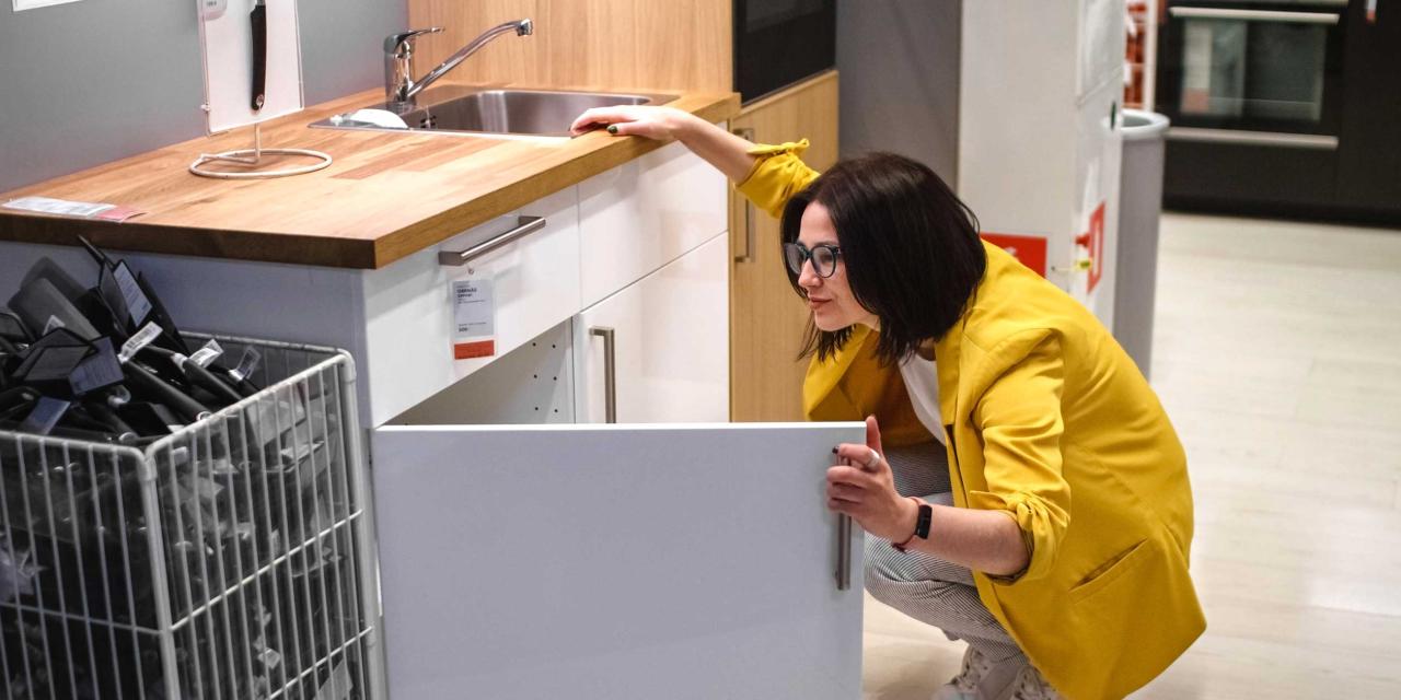 Frau schaut prüfend in einen Küchenschrank bei Ikea