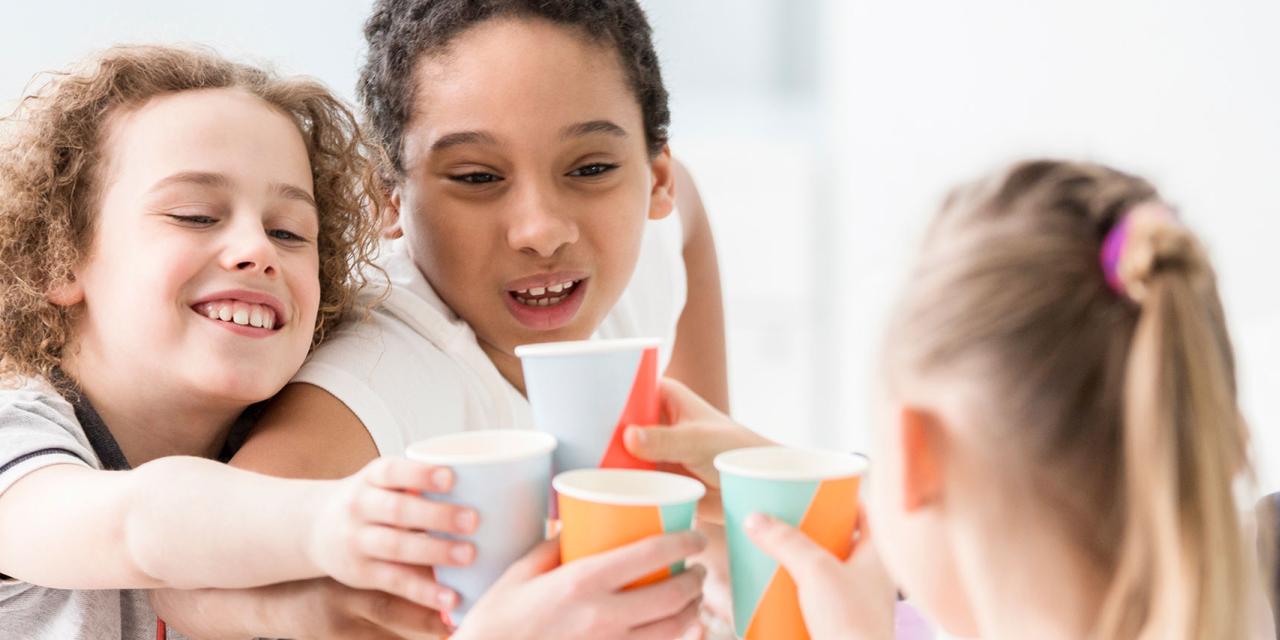 Mehrere Kinder stoßen mit Papbecherrn an