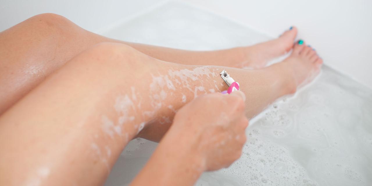 zwei Damenbeine in der Badewanne, Damenhand rasiert ein Bein