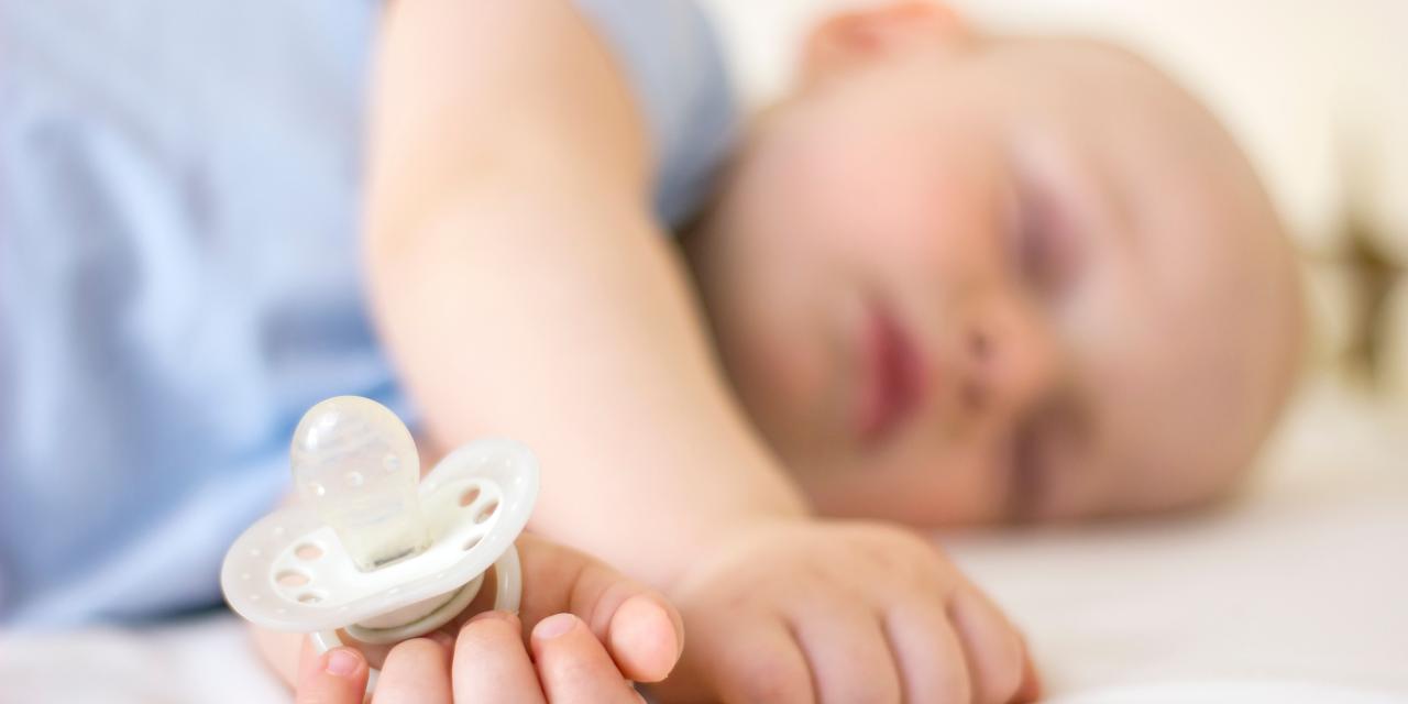 Ein friedlich schlafendes Baby mit einem Schnuller in der Hand