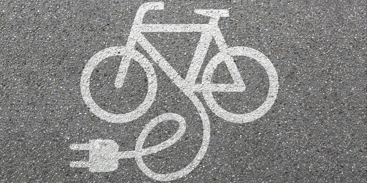 auf Asphalt weiß gesprühtes Fahrradsymbol mit Stecker daran