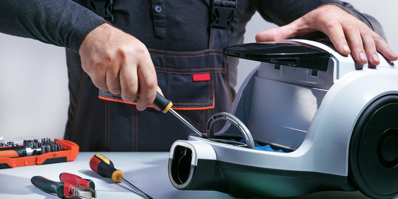 Ein Fachmann repariert einen Staubsauger. 