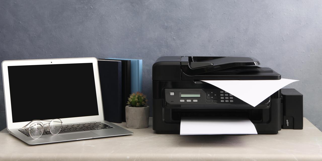 Ein Laptop und ein Drucker stehen auf einem Schreibtisch