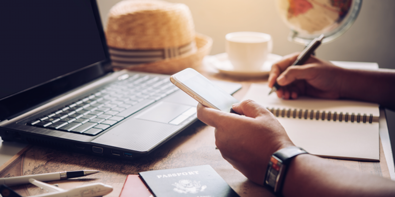 Man on laptop with smartphone in hand takes notes 