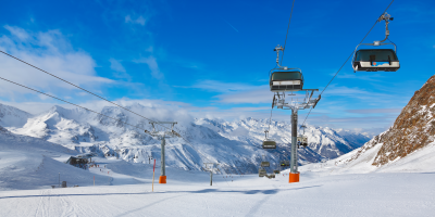 Eine Skipiste in den Bergen mit einem Sessellift darüber verlaufend.