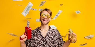 Gut gelaunter Mann mit Sonnenbrille und Leopardenshirt schießt Geldschscheine durch die Gegend
