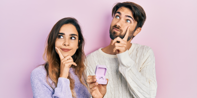 Ein Paar, das in einer überlegenden Pose mit einem Ehering in der Hand fotografiert wurde.