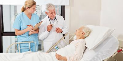 Arzt und DGKP in Spitalszimmer Patientin liegt im Krankenbett