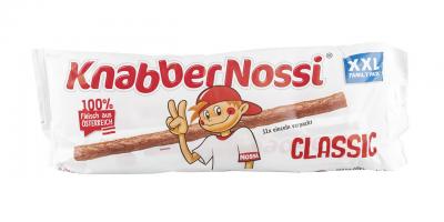 Knabber Nossi: weiße Verpackung mit aufgedruckter Wurststange, die ein Kind hält, rote Schrift