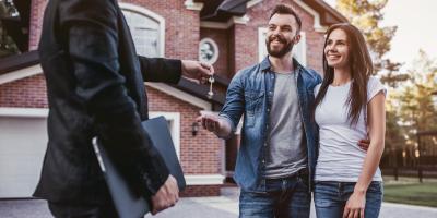 Immobilienkauf Schlüsselübergabe vor einem Haus Junges Paar lächelt Makler