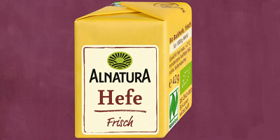 In gelbem Papier verpackter Hefewürfel mit der Aufschrift Alnatura Hefe frisch