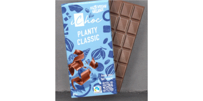 Eine Tafel iChoc „Planty Classic“ Schokolade. Die Verpackung ist blau mit braunen Schokoladenstücken und Blättermotiven. Es handelt sich um eine faire, vegane und biologische Schokolade. Neben der Verpackung ist die geöffnete Tafel mit rechteckigen Stücken sichtbar.