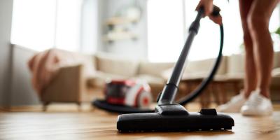 Person in Turnschuhe führt Staubsauger über Parkettboden