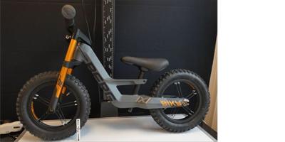 Graues Kinder-Laufrad von der Seite vor schwarzem Hintergrund