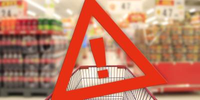 Einkaufswagen in Supermarkt (unscharf) mit rotem Gefahrendreieck mit Rufzeichen