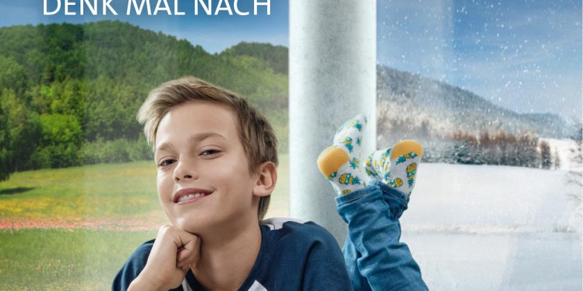 Bub liegt in einem Haus am Boden vor einer runden Betonsäule mit Blick ins grüne Land