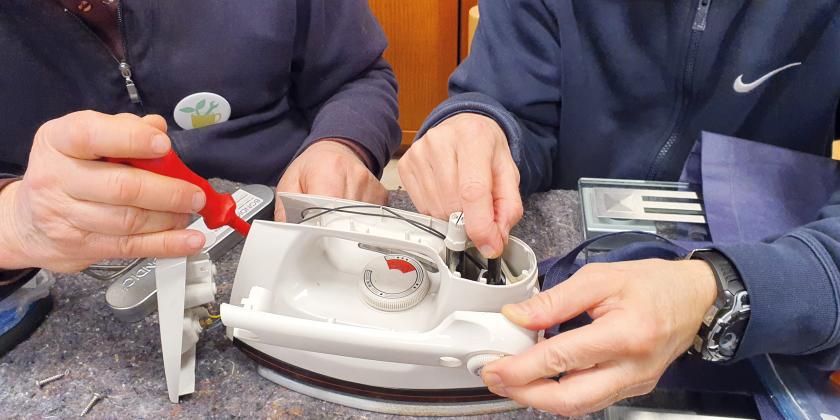 Zwei Männer reparieren ein Bügeleisen Nahaufnahme