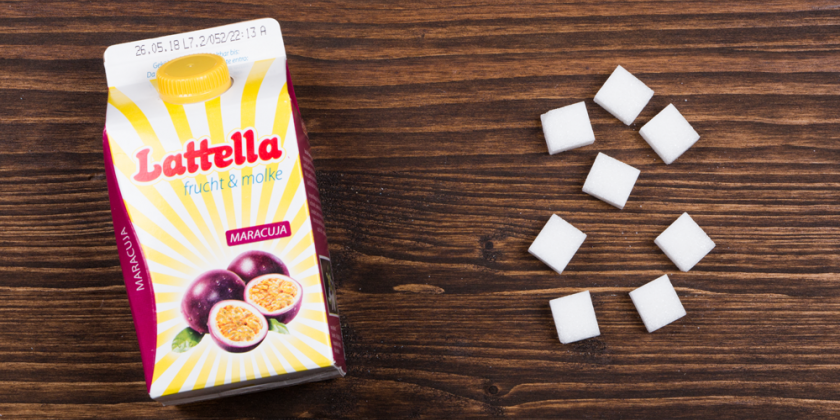 Latella-Fruchtmolkegetränk mit Zuckerwürfeln vor Holzhintergrund