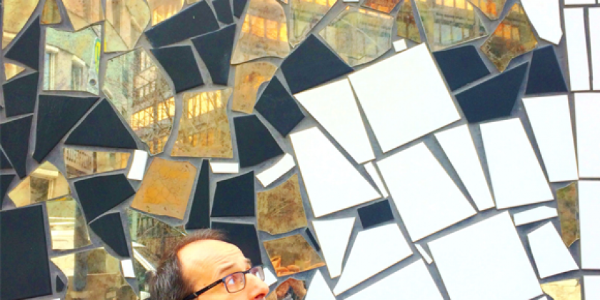 Ein Mann vor einer Mosaik-Spiegelwand.