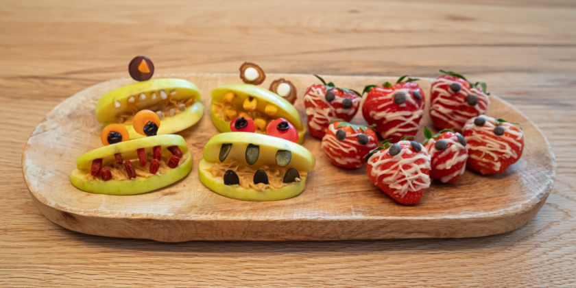 Geschnitzte Apfel-Monster und Erdbeer-Mumien auf Teller