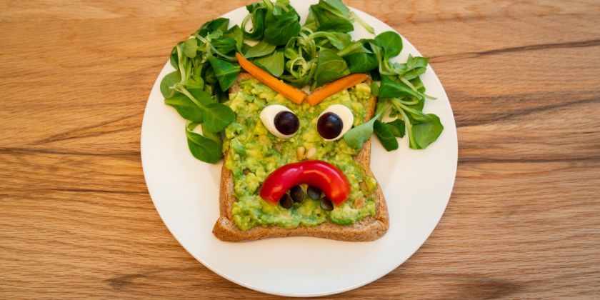 Avocado-Toast mit Gemüsegesicht und Vogerlsalat-Haarpracht auf Teller