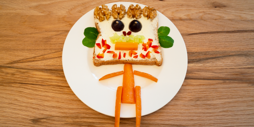 Frischkäse-Toast mit Gemüsegesicht und Karottenkörper