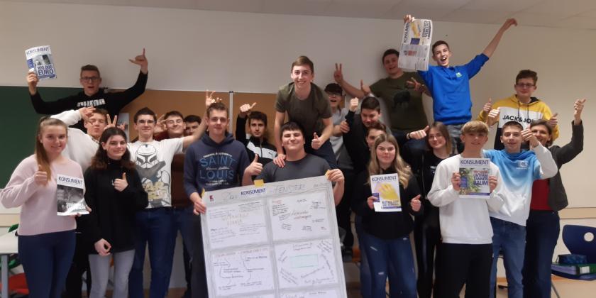 Schulklasse stehend mit großem Plakat