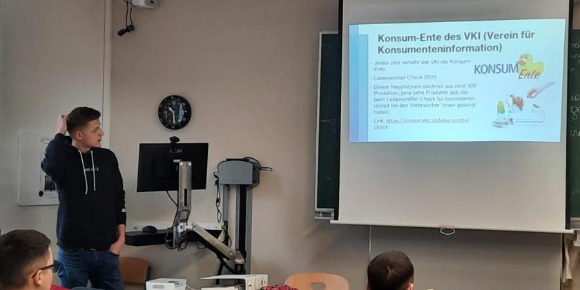 Lehrer und 2 Schüler schauen zu Arbeitsblatt projiziert auf Leinwand