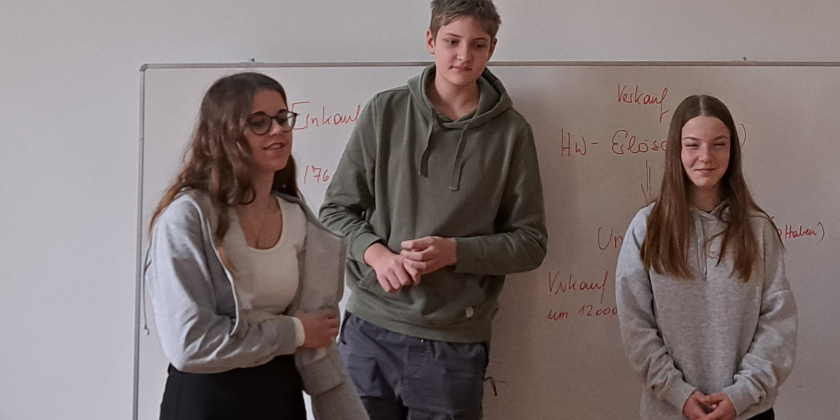 3 Schüler:innen unter Projektion zum Warenkorb