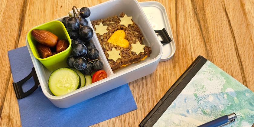 Vollkornbrot mit Hummus und Käsesternen, Weintrauben, Datteln, Gurkenscheiben und Tomate