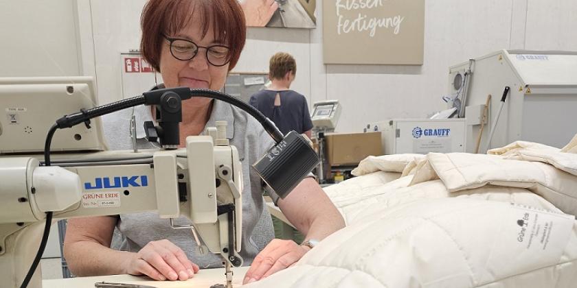 Mitarbeiterin von Grüne Erde näht mit der Nähmaschine einen Kopfpolster zu