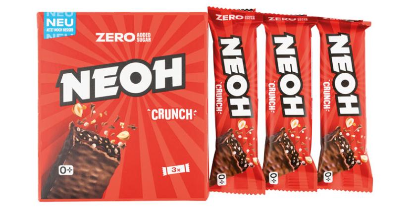 Drei NEOH Crunch Riegel in Plastikverpackung neben der Kartonverpackung in rotem Design vor weißem Hintergrund.